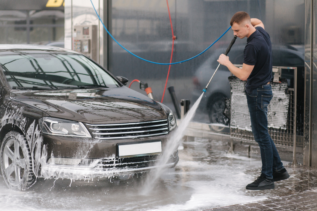 Worker Cleaning Car Using High Pressure Water